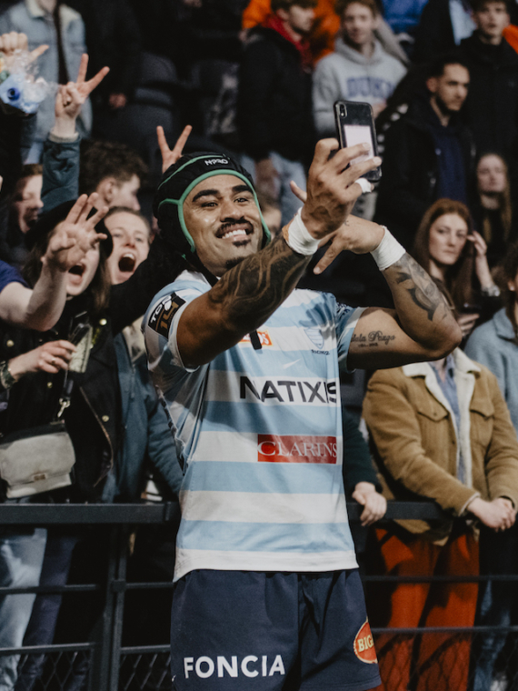 A rugby player taking a selfie with supporters during a match