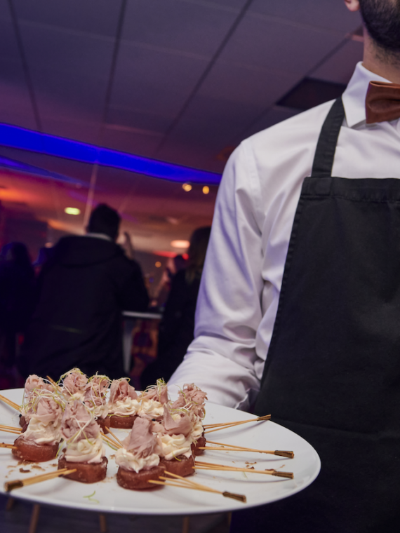 Waiter serving petits-fours at the Cocktail in the Salon Partagé Salon des Lumièes at Groupama Stadium during a Sodexo Live Hospitality event.