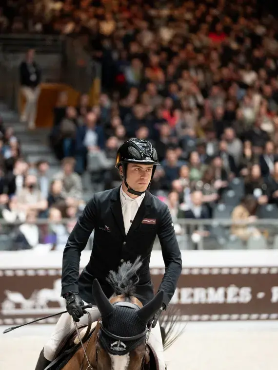 Cavalier en plein saut d’obstacle lors du CSI 3* au Salon du Cheval, performance sportive de haut niveau accessible en VIP.