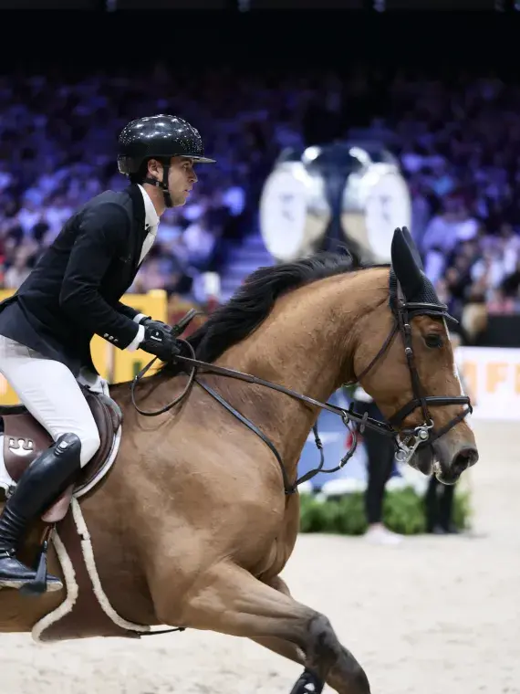 Cavalier concentré en pleine performance de saut d’obstacle, instant suspendu capté au Salon du Cheval de Paris.
