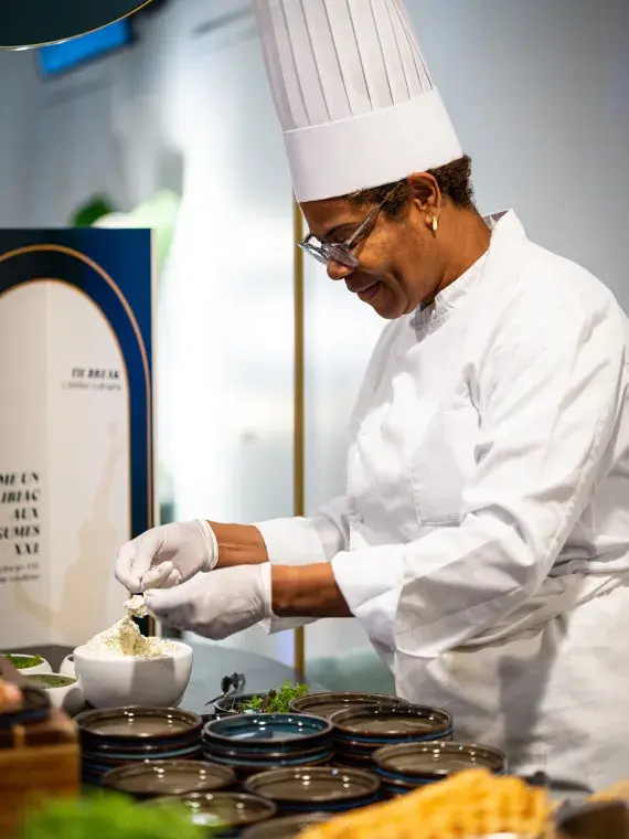 Chef du Salon Tie-Break en train de préparer des desserts, mettant en valeur le savoir‑faire culinaire de Sodexo Live! Hospitality. 