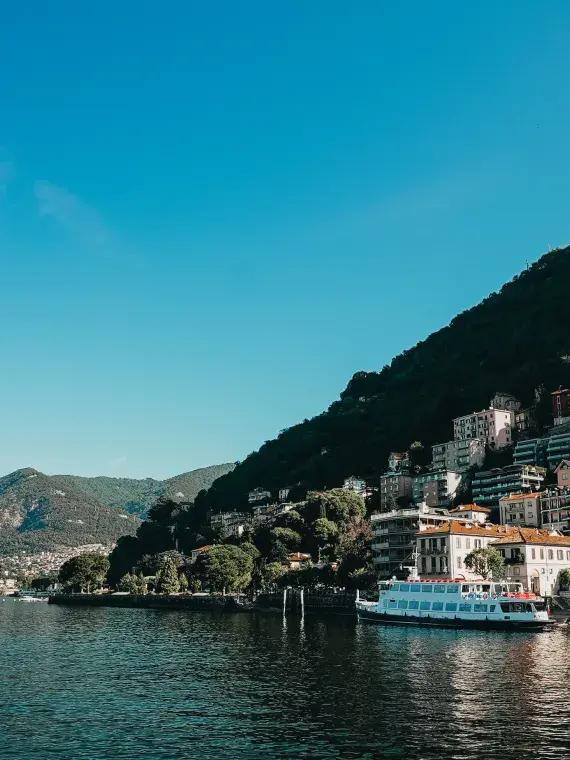 Boat sailing on Lake Como, surrounded by mountains, illustrating the cruise included in Sodexo Live! Hospitality’s VIP offers.
