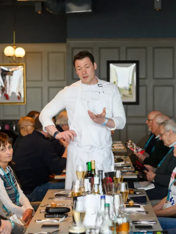 Le chef Tommy Banks échange avec les invités VIP dans un salon hospitalité des Finales du Nations Championship.