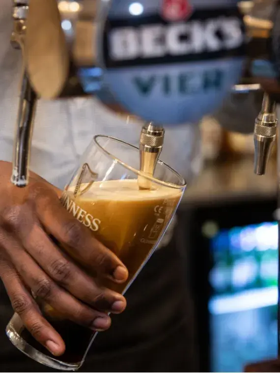 Barman servant une bière à un invité dans un salon VIP Sodexo Live! Hospitality, illustrant l’ambiance conviviale du rugby à Twickenham.