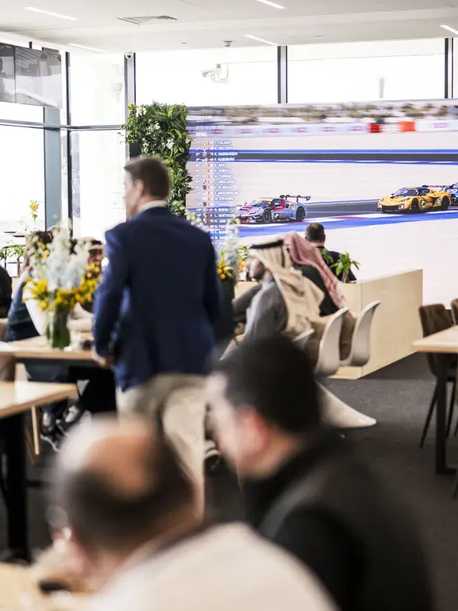 Fans enjoying a meal inside the VIP lounge while watching the WEC race on a giant 4K screen, showcasing the premium experience provided by Sodexo Live! Hospitality