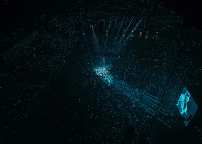concert gims vip paris la defense arena_0.jpg Concert VIP de Gims à la Paris La Défense Arena, avec la scène illuminée et une foule enthousiaste.
